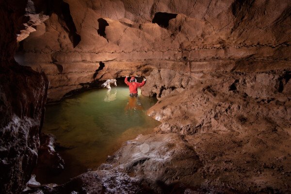 Passage de la voûte mouillante, un spéléo avec de l'eau jusqu'au ventre. (Baume Chazelle, Ardèche)