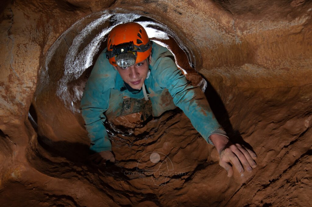 Un spéléo dans une petite conduite forcée. (Grotte de Baumas, Ardèche)