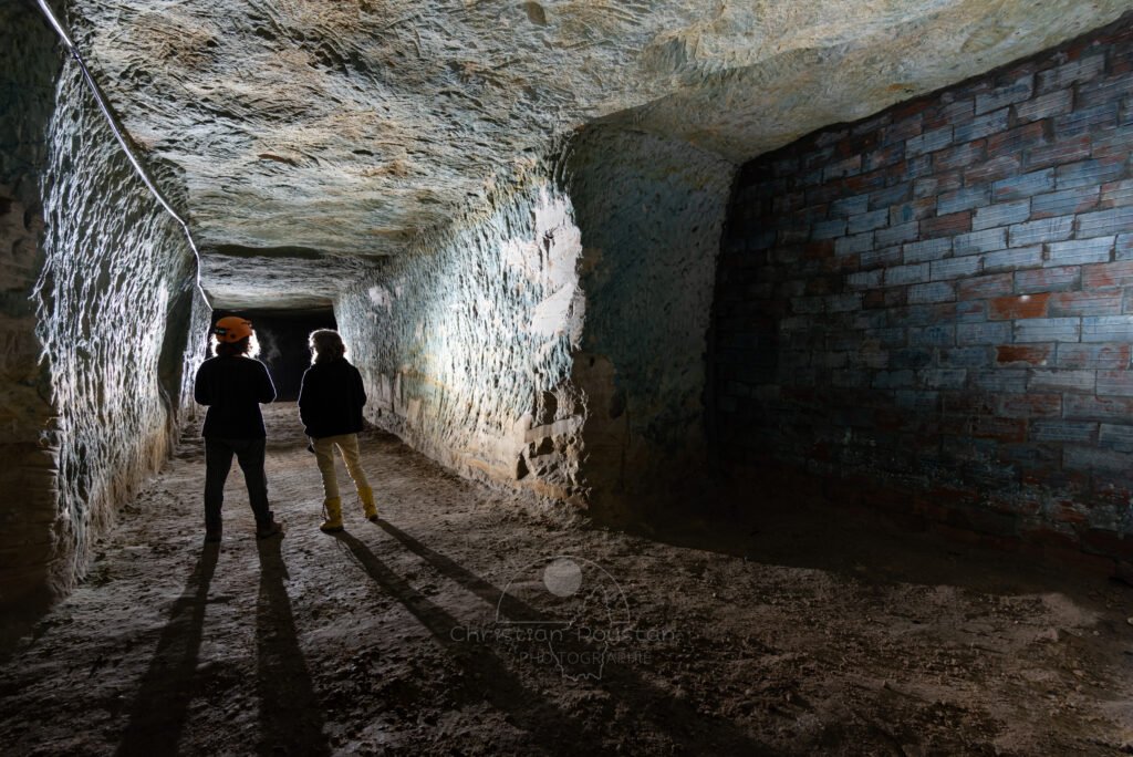 Une grande galerie colorée au sulfate de cuivre. Avec au premier plan un mur en brique. (Carrière de Saint-Pancrace, Gard)