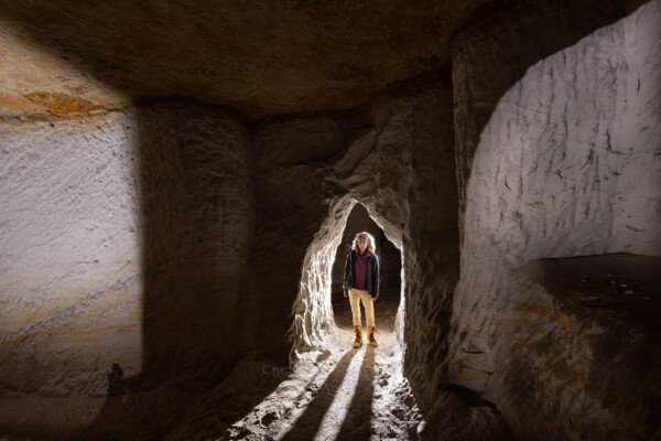 Petit passage de jonction entre deux galeries, avec un spéléo. (Carrière de Saint-Pancrace, Gard)