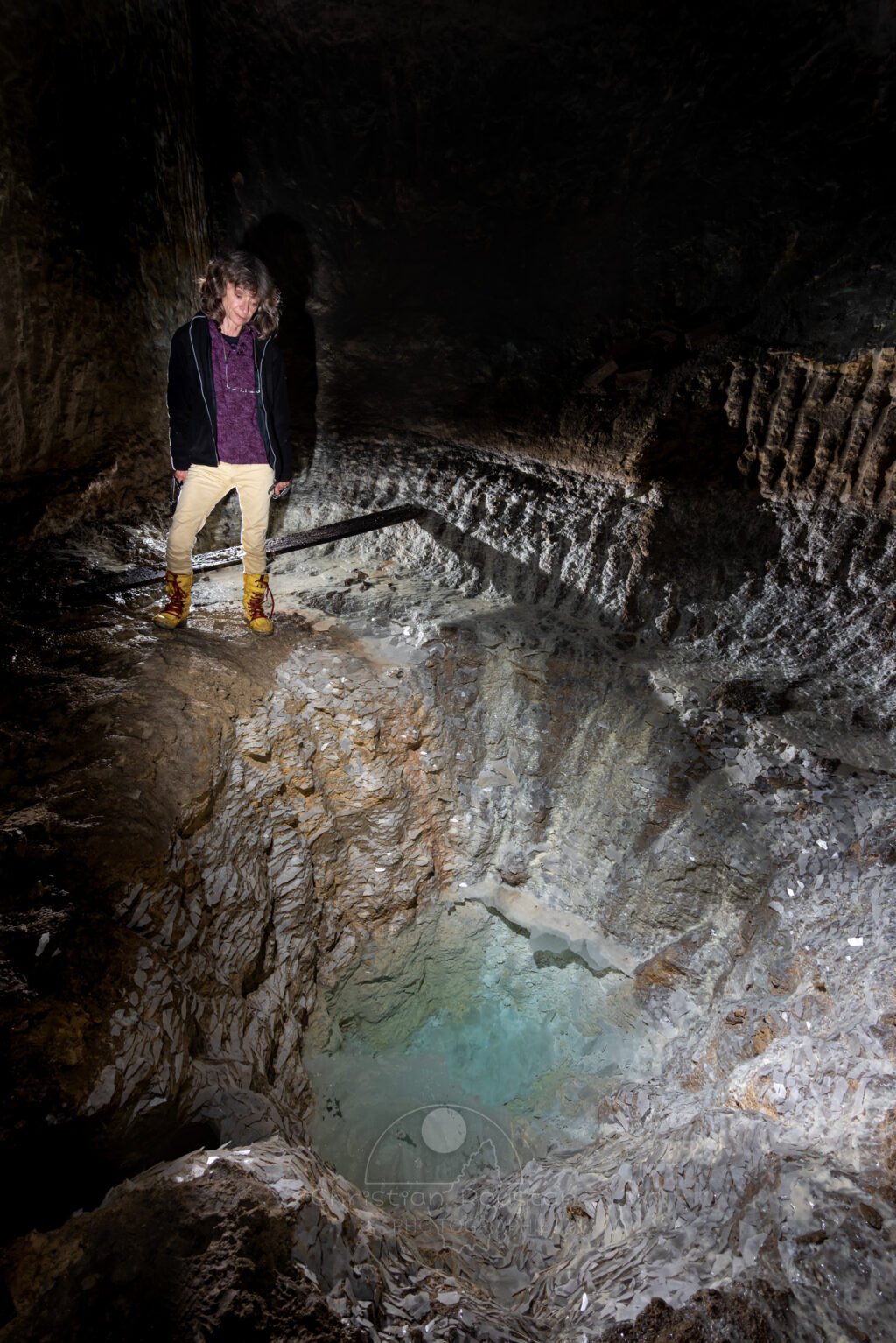 Une spéléologue regarde l'eau bleue turquoise au fond du puits. (Carrière de Saint-Pancrace, Gard)
