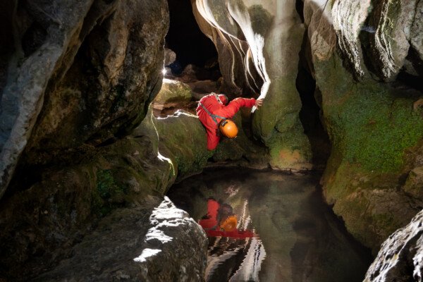Plouf... ou pas... Reflet d'un spéléo qui se penche dans une vasque à la sortie de la Dragonnière de Banne. (Dragonnière de Banne, Ardèche)