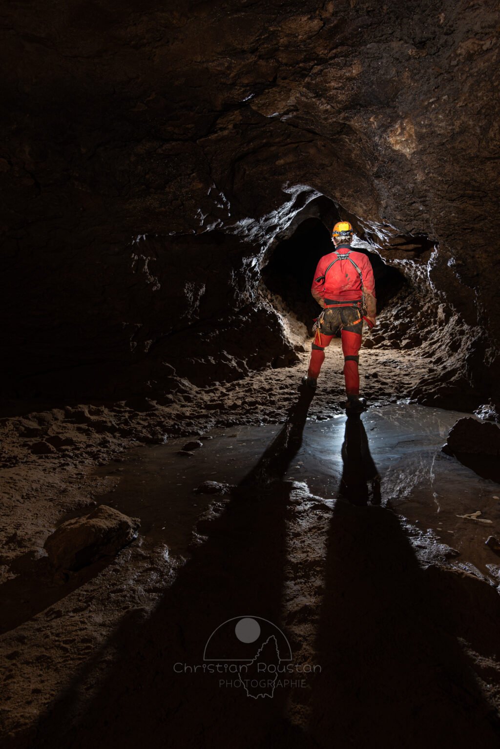 Un spéléo dans la galerie d'accès au P10 (Avec une flaque derrière lui). (Évent de Foussoubie, Ardèche)