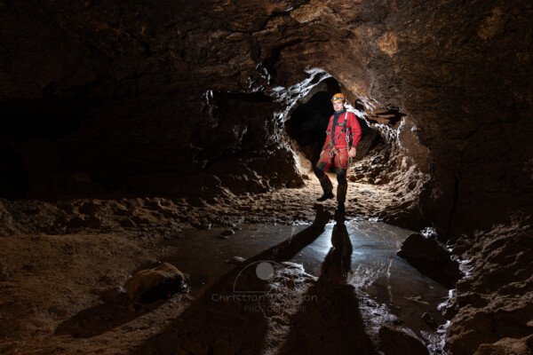 Un spéléo dans la galerie d'accès au P10 (Avec une flaque devant lui). (Évent de Foussoubie, Ardèche)