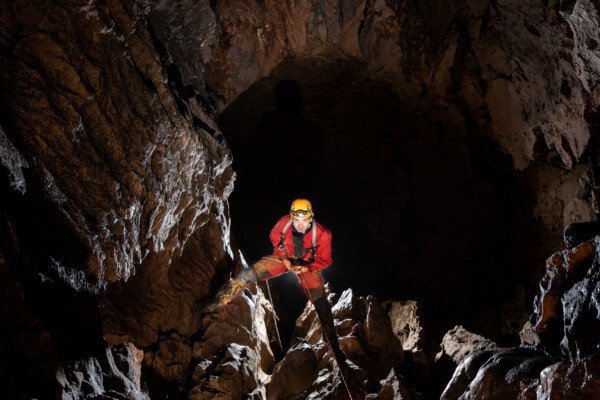 Un spéléo descend un puits. Le qui n'est pas éclairé est tout noir. (Évent de Foussoubie, Ardèche)