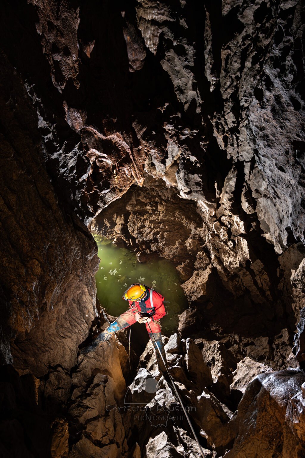 Un spéléo descend un puits. Au fond il y a de l'eau. (Évent de Foussoubie, Ardèche)