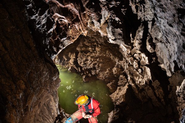 Un spéléo descend un puits. Au fond il y a de l'eau. (Évent de Foussoubie, Ardèche)