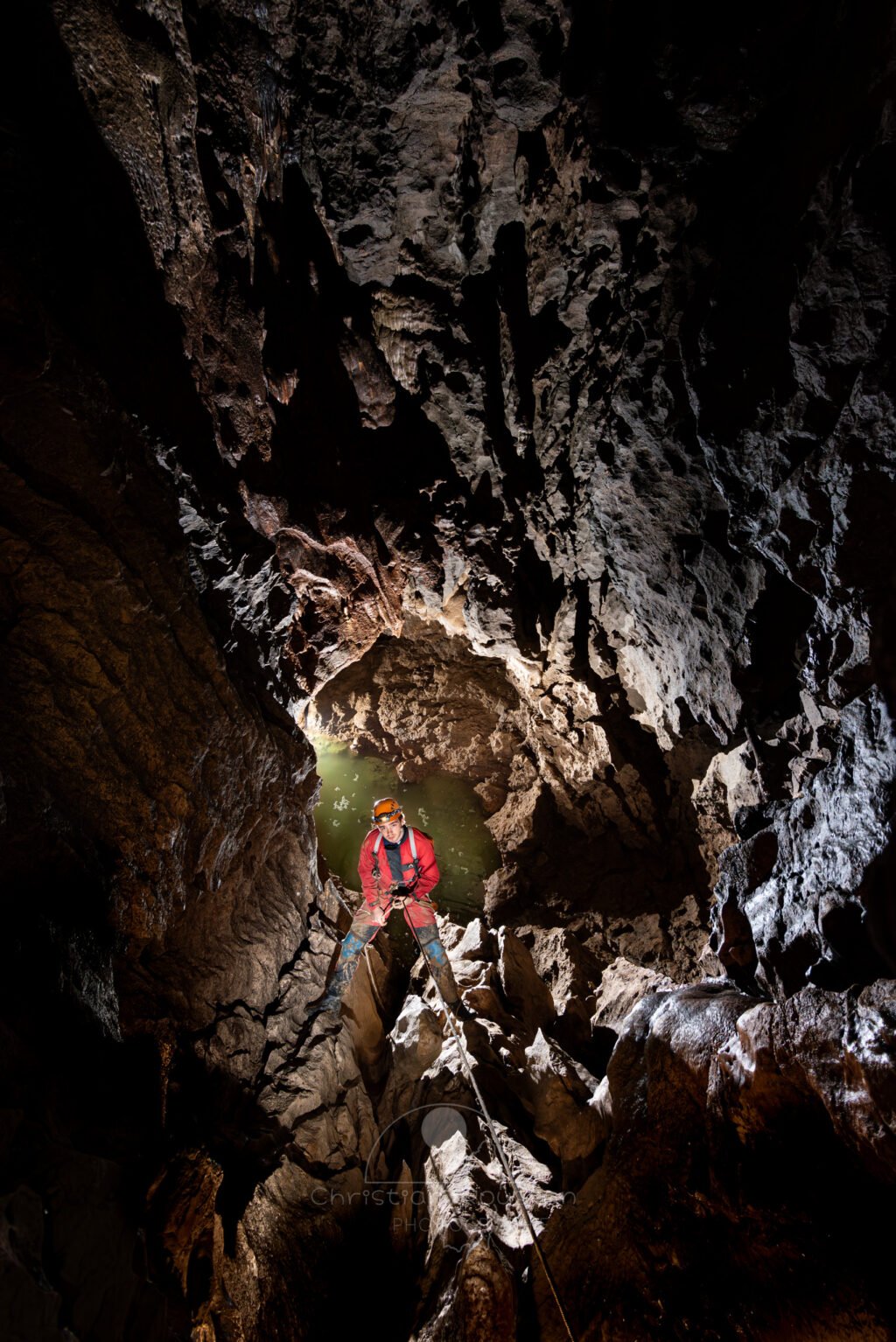 Un spéléo descend un puits. Au fond il y a de l'eau. (Évent de Foussoubie, Ardèche)