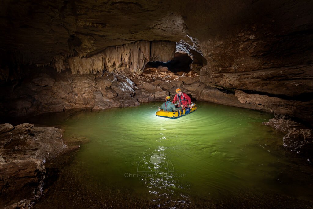 Deux spéléo dans un bateau pneumatique sur un lac avec une eau verte. (Évent de Foussoubie, Ardèche)