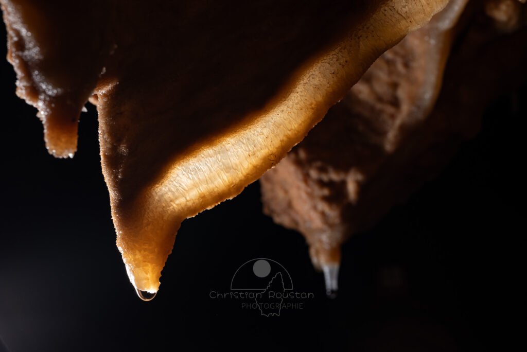 Draperie, éclairée par transparence on découvre la structure cristalline. (Grotte Flandin, Ardèche)