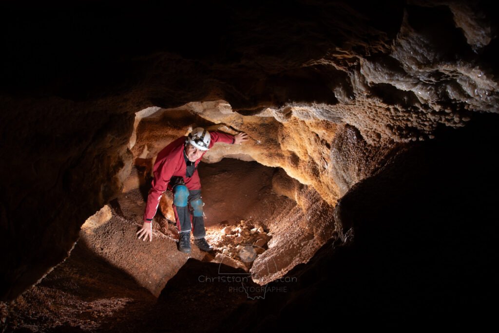 Vue sur cette minuscule salle couverte de cristaux. Le spéléo et photographe Christian Roustan pose sur la photo. (Grotte de Champlong, Ardèche)