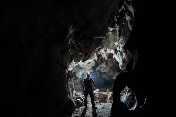 Vision monochrome d'un spéléo dans une galerie. (Grotte des Fées, Ardèche)