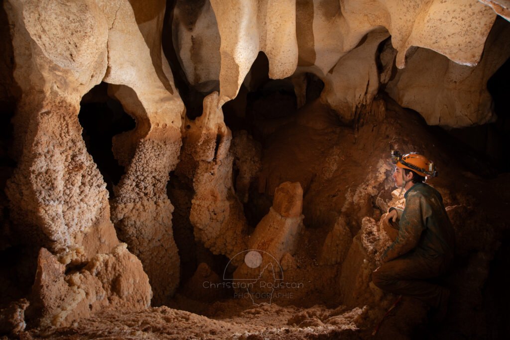Des cristaux dans un gour asséché avec spéléo au bord. (Grotte du Barry, Gard)