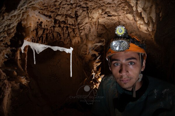 Un spéléo pose à coté d'un fragile spéléothème. (Grotte du Barry, Gard)