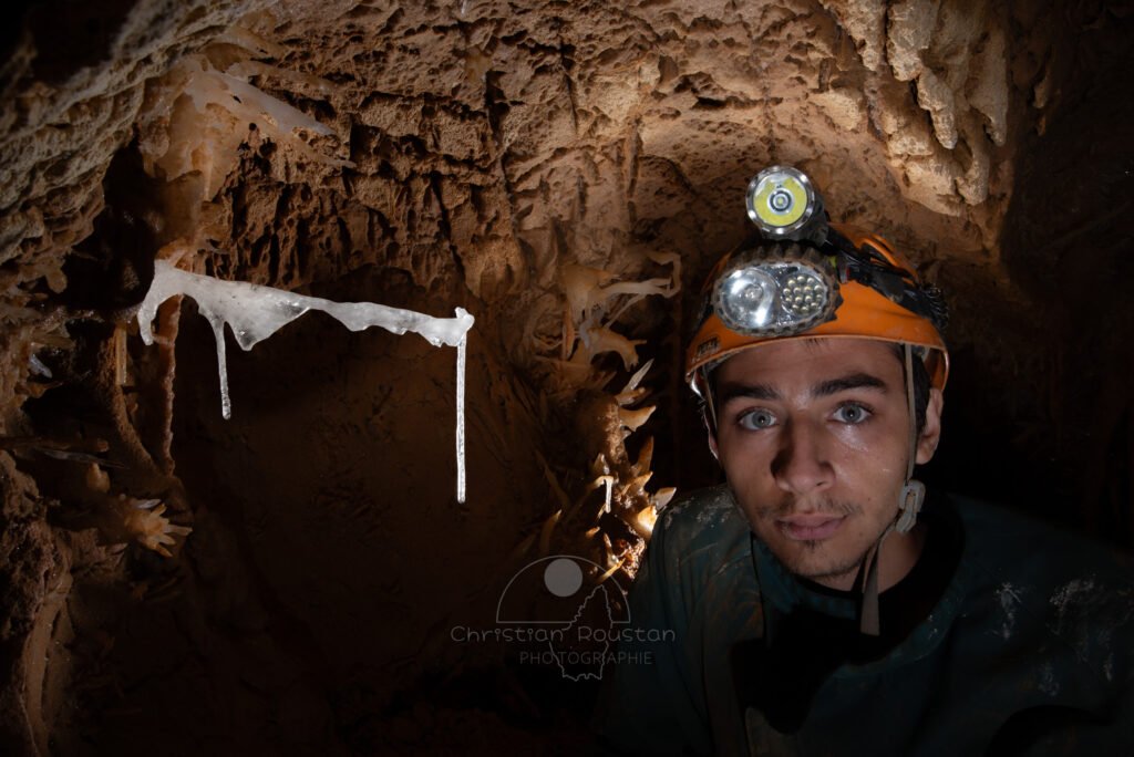 Un spéléo pose à coté d'un fragile spéléothème. (Grotte du Barry, Gard)
