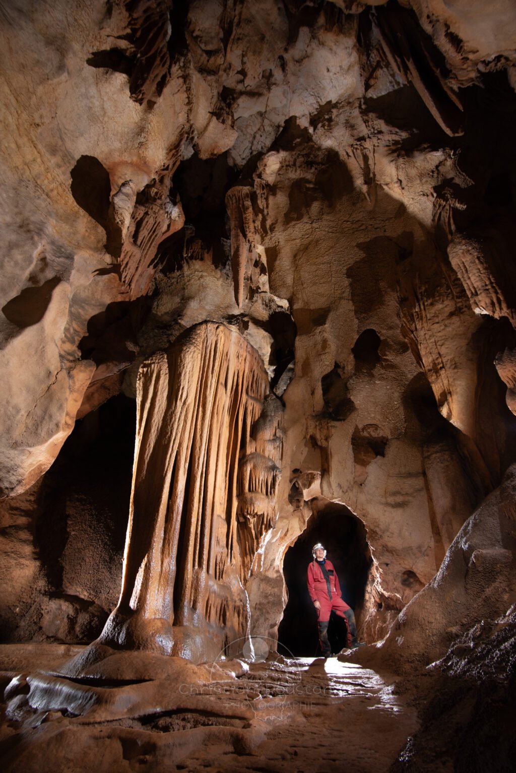 Spéléo dans la grande du Barry, le passage entre les concrétions ressemble à une porte.. (Grotte du Barry, Gard)