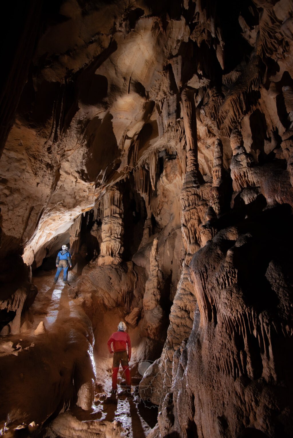 La salle Mazauric (Grotte du Barry) et ses massifs stalagmitiques avec deux spéléos. (Grotte du Barry, Gard)