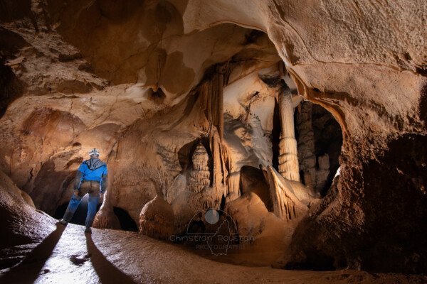 Fenêtre sur la grande salle du Barry avec un seul spéléologue en bleu. (Grotte du Barry, Gard)