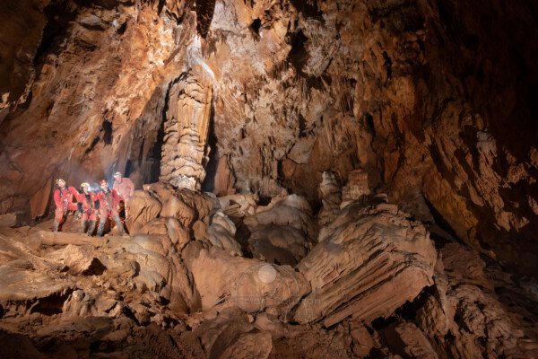 "ça penche..." Un groupe de spéléologues posent à coté du grande concrétion qui penche. (Grotte du Chasserou, Ardèche)