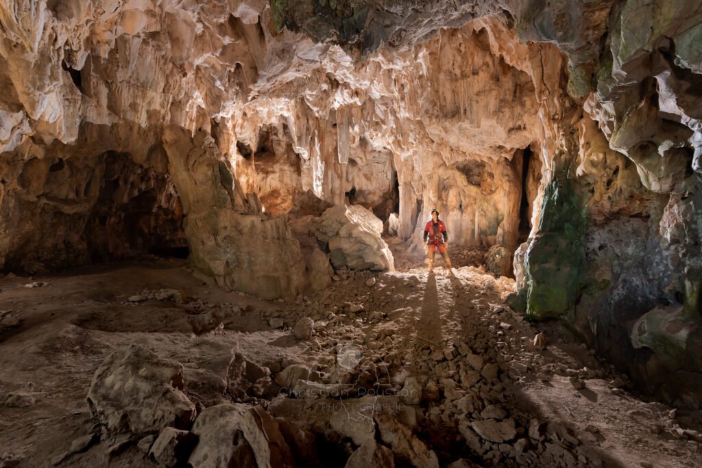 La salle d'entrée avec spéléo au fond. (Grotte du Chasserou, Ardèche)