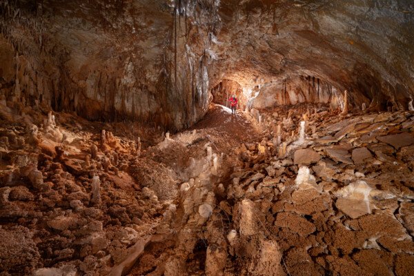 La première salle avec un spéléo à la base du puits d'entrée. (Aven Grotte de l'Émeraude, Gard)