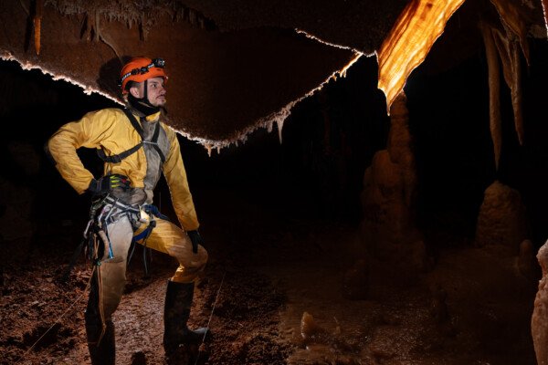 Un spéléo admire une belle draperie éclairée par transparence. (Spéléothème) (Aven Grotte de l'Émeraude, Gard)