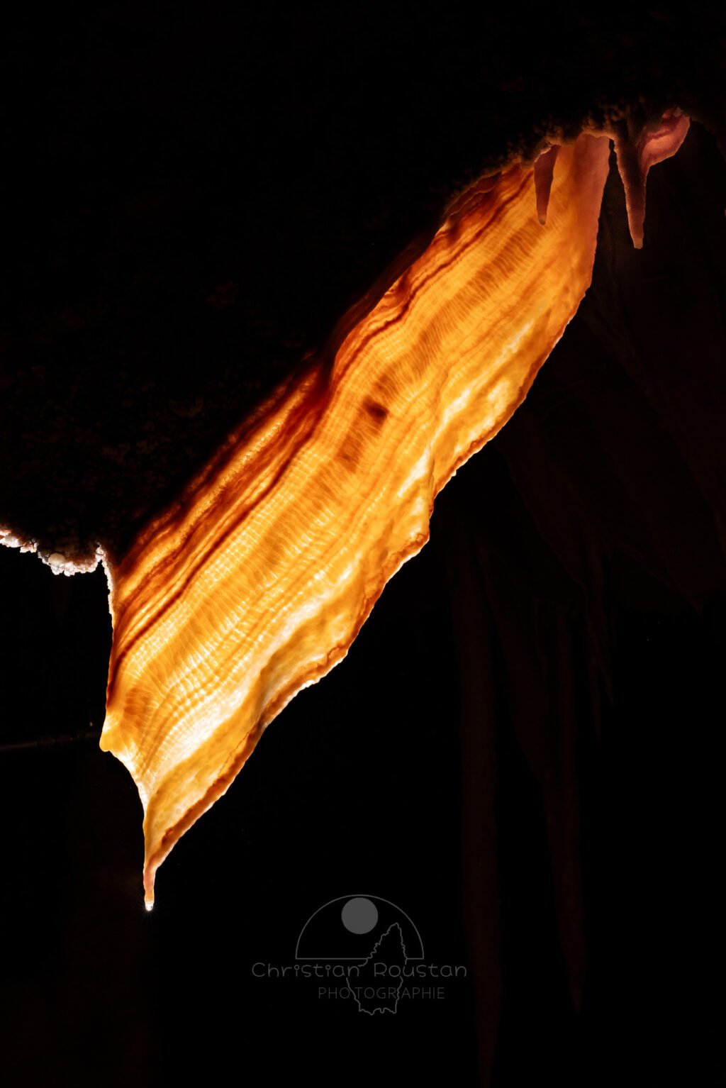 Une draperie éclairée par transparence. (Spéléothème) (Aven Grotte de l'Émeraude, Gard)