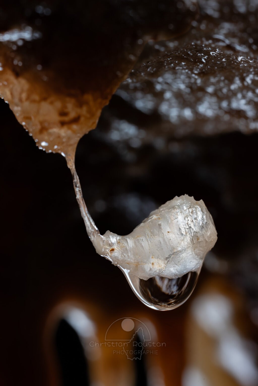 Une goutte d'eau suspendue par un mince fil de calcite. (Spéléothème) (Aven Grotte de l'Émeraude, Gard)