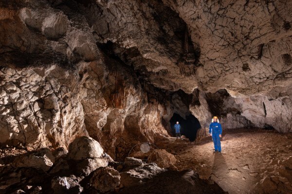 A proximité de l'entrée, deux spéléo en bleu. (Grotte de Louoï, Ardèche)