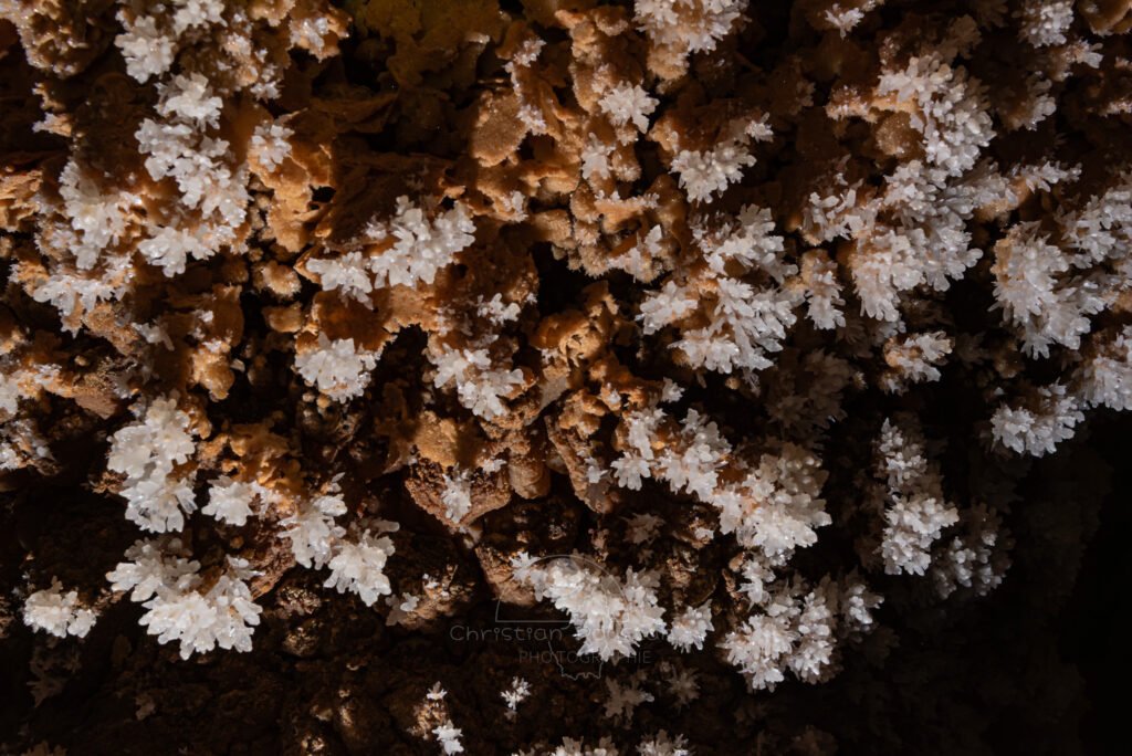 Cristaux blancs sur la paroi ocre (Spéléothème, Grotte de l'interrogation, Gard)