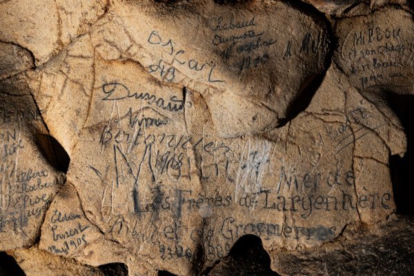 Les visiteurs ont laissé leur nom sur la paroi. (Aven Grotte Nouvelle, Ardèche)