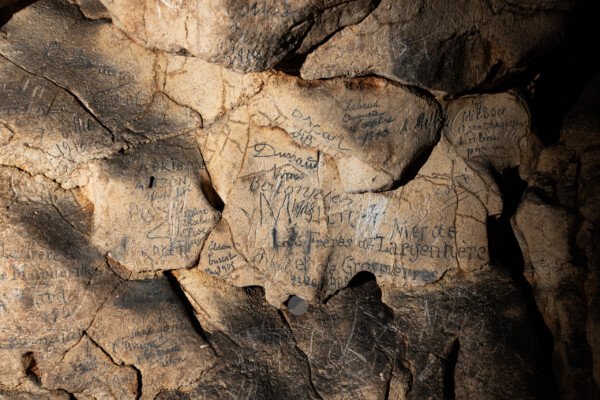 Les visiteurs ont laissé leur nom sur la paroi. (Aven Grotte Nouvelle, Ardèche)