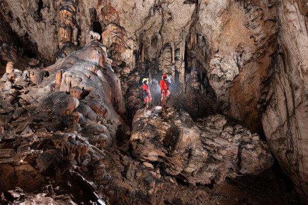 Deux spéléologues dans la première salle avec le grand pilier effondré (Aven Grotte Nouvelle, Ardèche)