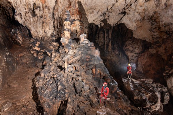 Deux spéléologues dans la première salle avec le grand pilier effondré (Aven Grotte Nouvelle, Ardèche)