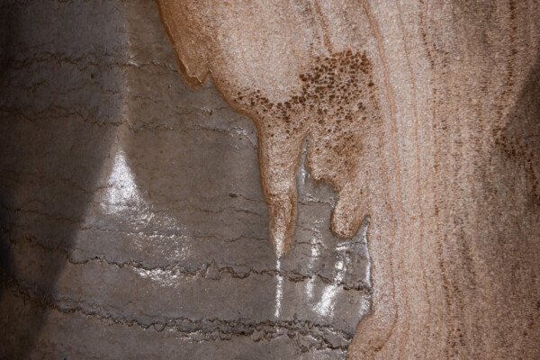 La paroi laisse apparaître des variations de couleur et de texture. (Réseau de la Cocalière, Résurgence de la Cotepatière, Aven de la Courcalhère, Ardèche)