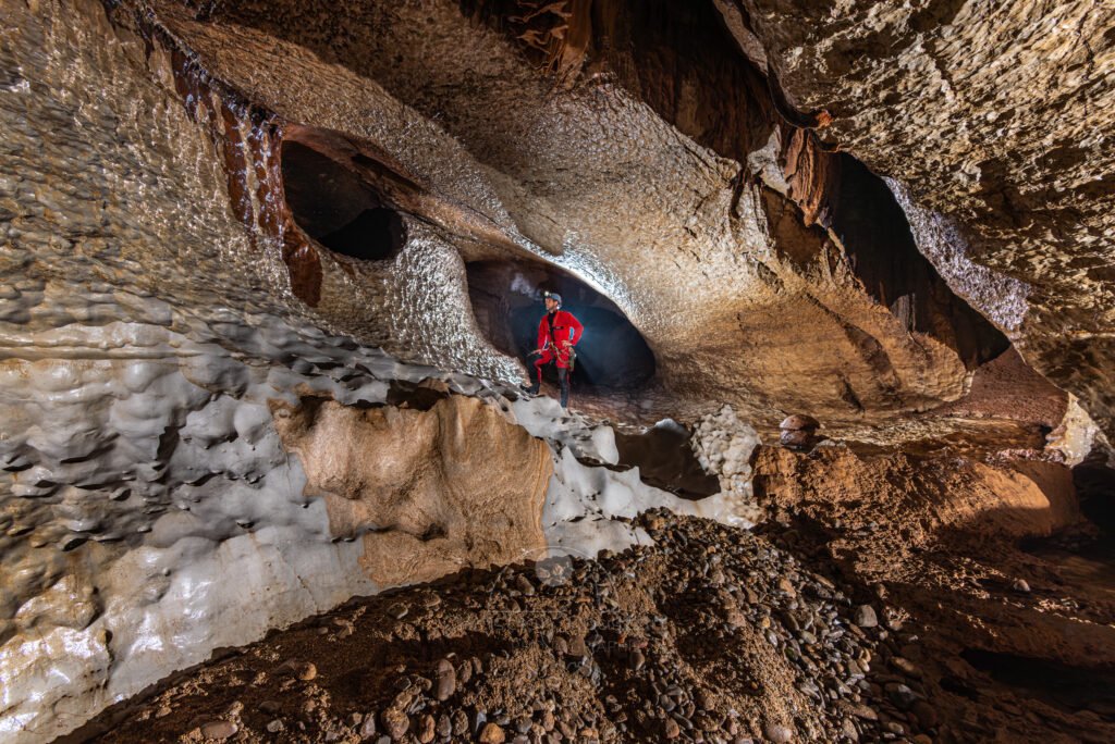 Un profil de galerie à 45°. Du sable et des galets au premier plan (Évent de Peyrejal, Ardèche)