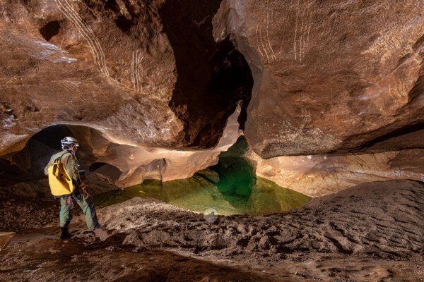 Un spéléo regarde la dernière vasque avant le siphon (Peyrejal, Ardèche)
