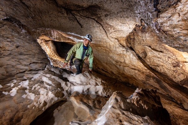 Progression d'un spéléo dans la galerie érodé par l'eau (Évent de Peyrejal, Ardèche)