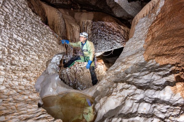 Petit passage en main courante avec reflet du spéléo dans une vasque (Évent de Peyrejal, Ardèche)