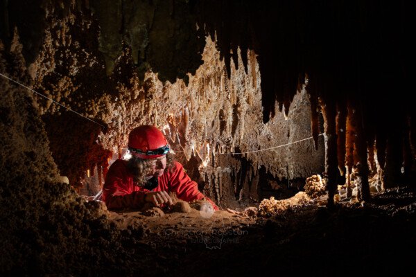 Spéléo dans un passage bas concrétionné (Grotte de la Barbette, Réseau Estevan, Gard)