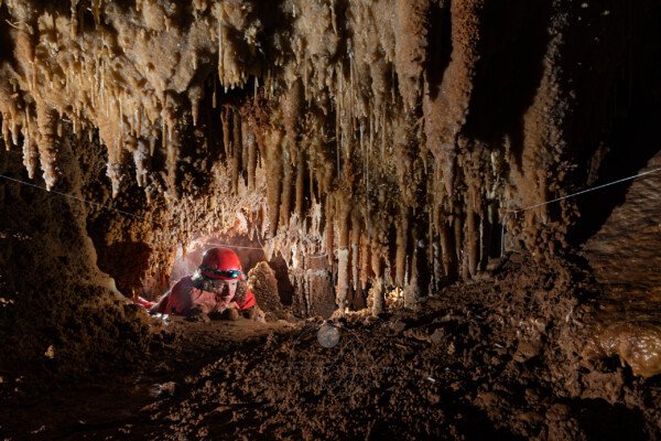 Pause contemplation d'une spéléo dans un passage bas concrétionné (Grotte de la Barbette, Réseau Estevan, Gard)