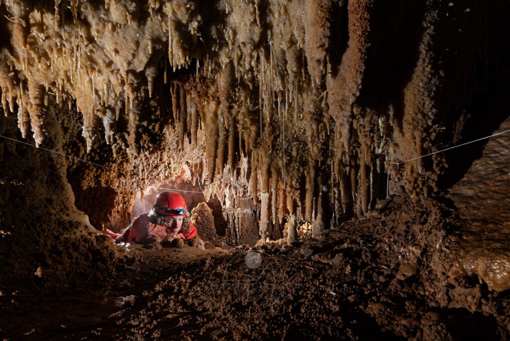 Pause contemplation d'une spéléo dans un passage bas concrétionné (Grotte de la Barbette, Réseau Estevan, Gard)