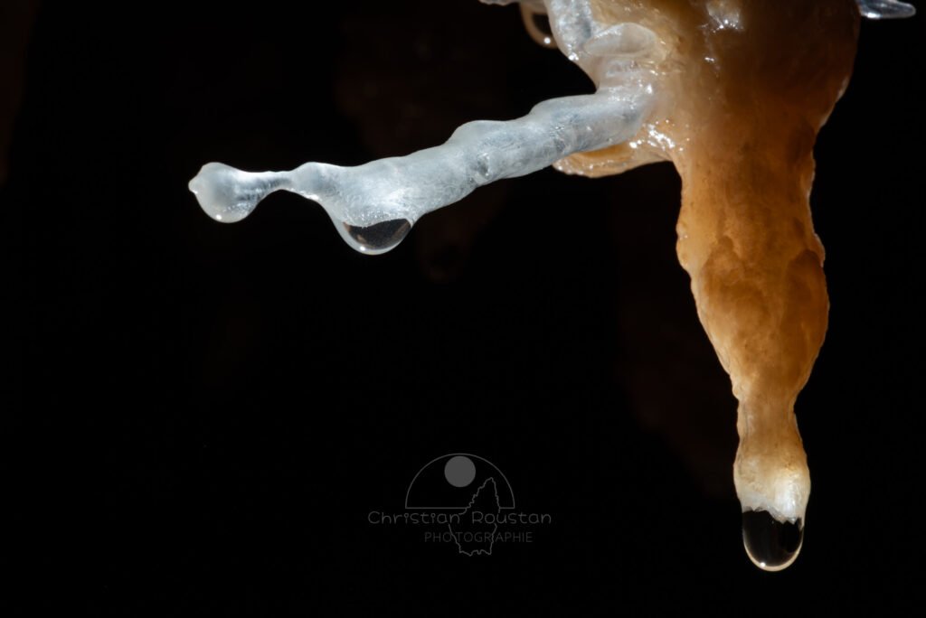 Une stalactite ocre avec une excentrique blanche (Grotte de la Barbette, Réseau Estevan, Gard)