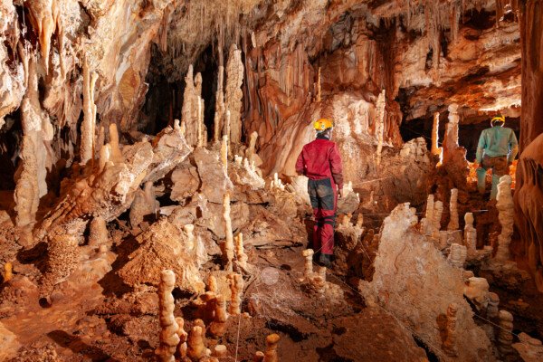 Une salle concrétionnée avec un spéléo qui suit le balisage (Grotte de la Barbette, Réseau Estevan, Gard)