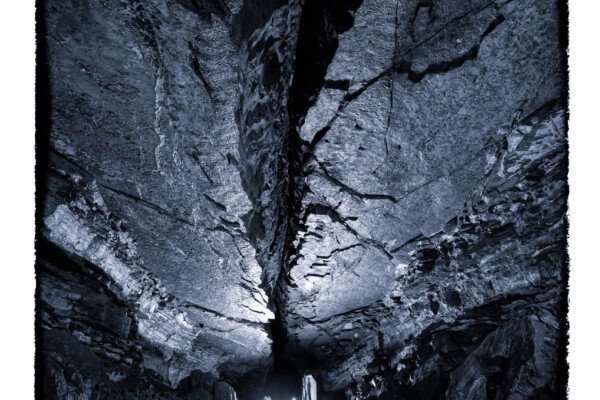 Un spéléo dans une belle galerie au plafond lisse coupé par une grosse fracture (Grotte de Pézenas, Ardèche)