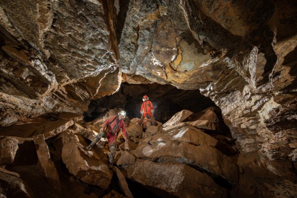 Des spéléo franchissant une zone chaotique qui barre la galerie (Grotte de Pézenas, Ardèche)