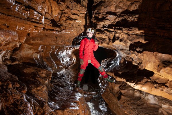 Profil de galerie avec banquette avec un spéléo en opposition (Grotte de Pézenas, Ardèche)