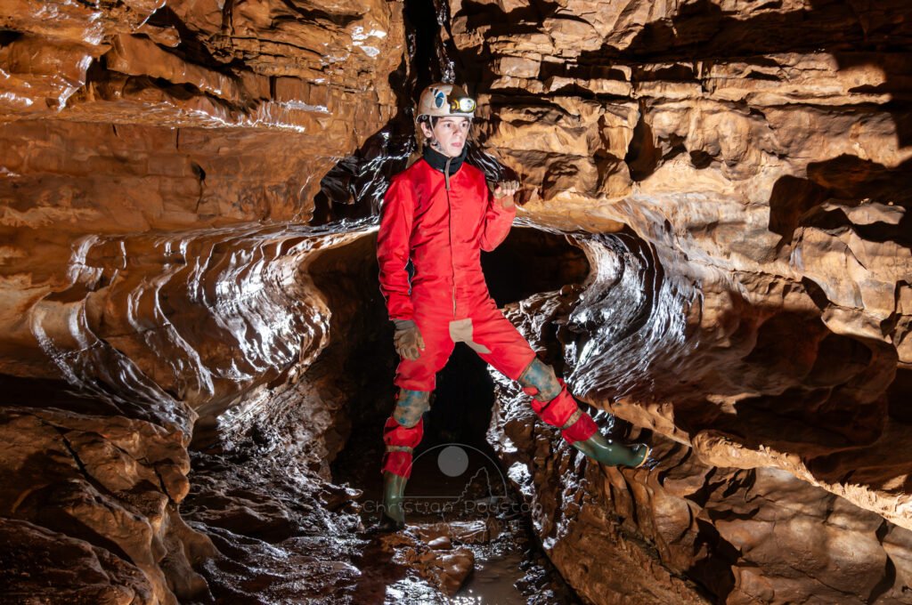 Profil de galerie avec banquette avec un spéléo en opposition (Grotte de Pézenas, Ardèche)
