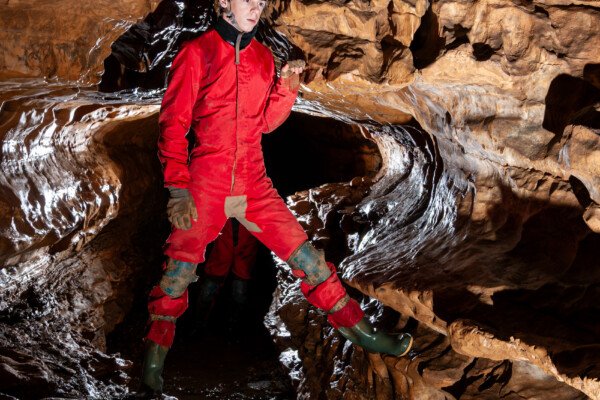 Profil de galerie avec banquette avec un spéléo en opposition (Grotte de Pézenas, Ardèche)
