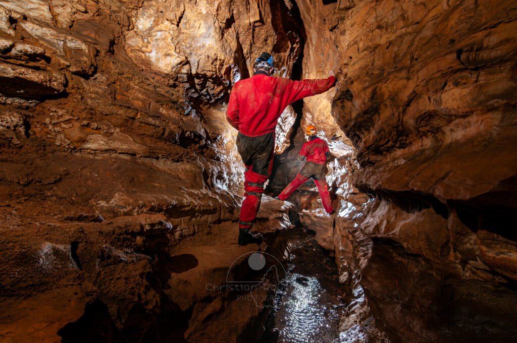Deux spéléo se suivent en passant en hauteur sur des banquettes (Grotte de Pézenas, Ardèche)
